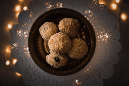 Sumptuous dessert balls - ladoos, elegantly presented on an intricate doily with ambient lighting.