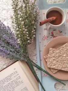 A cozy breakfast setup with tea, lavender flowers, and a book for a relaxing morning.