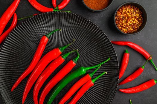 A wooden block with a plate of whole red chilies and a small bowl of red chili flakes. The bright red color and spicy ingredients visually represent heat and intensity, symbolizing Pitta‑related vertigo triggers.