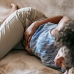 Woman sleeping with hands resting on her stomach, representing sleep changes during the menstrual cycle.
