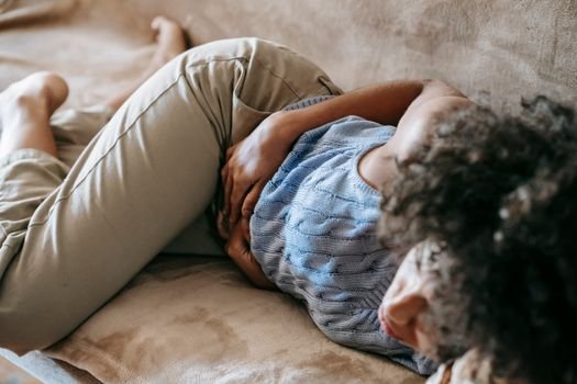 Woman sleeping with hands resting on her stomach, representing sleep changes during the menstrual cycle.