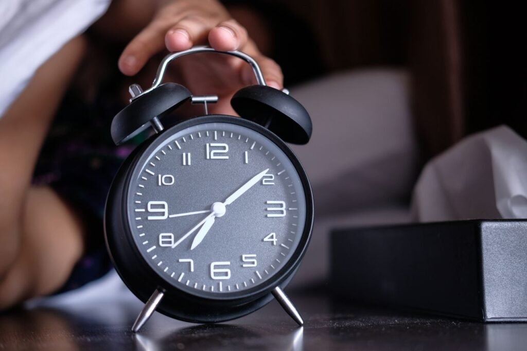Analog alarm clock showing 10 minutes part 7, a hand stopping the alarm.