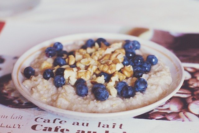 A bowl of warm oatmeal breakfast topped with nuts- walnuts and blueberries - for steady energy.