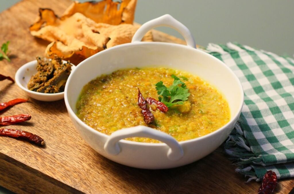 Khichari - Kitchari a simple rice and moong lentil porridge with ghee, served in a white bowl.